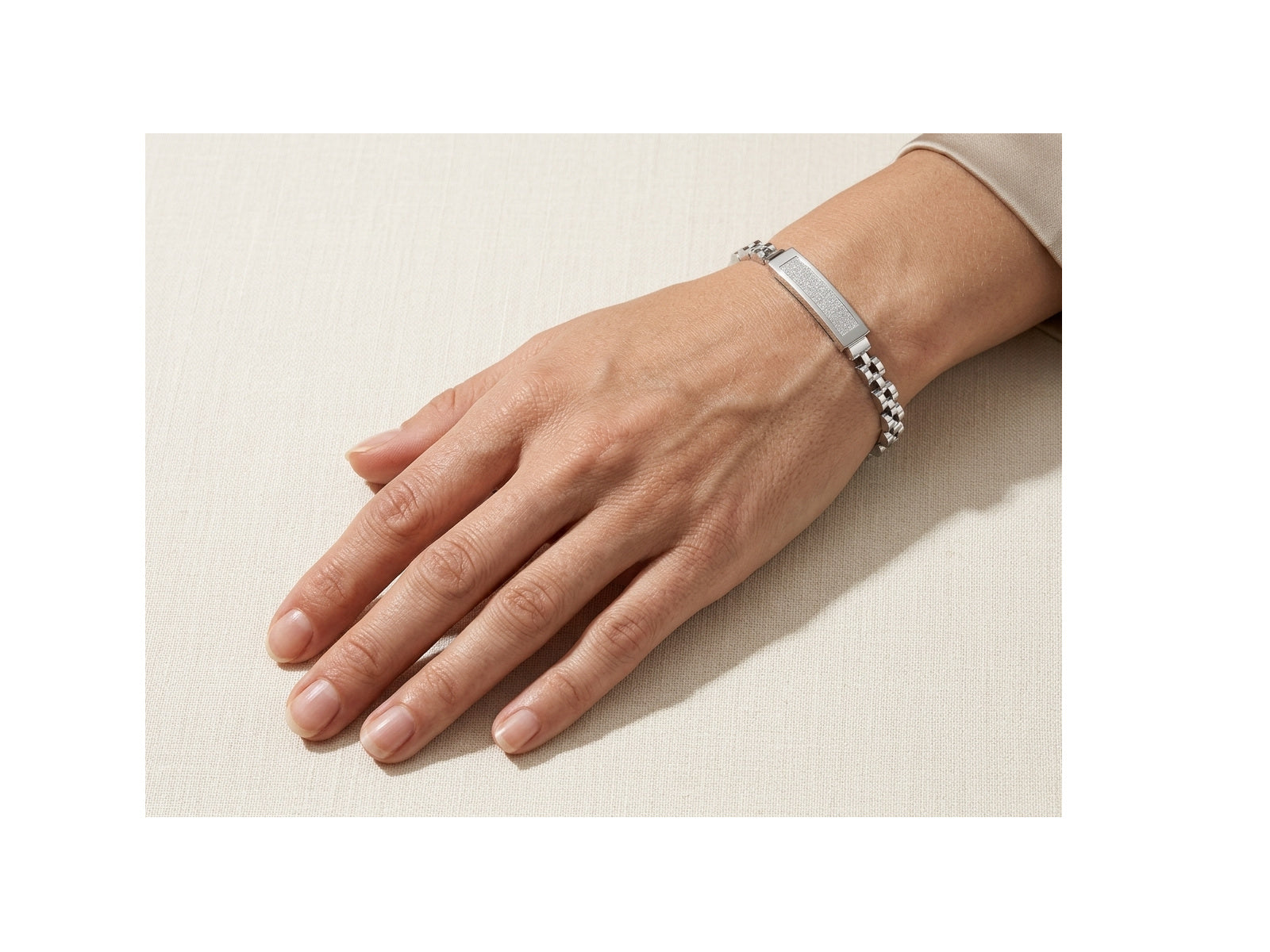 Hand wearing a silver bracelet on a light background